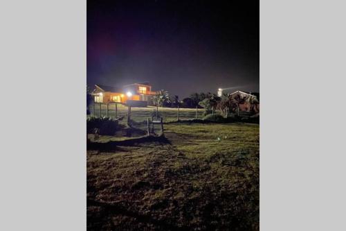 a yard at night with a house in the background at Tamassa Holiday Home on the Beach, in Port Edward in Port Edward
