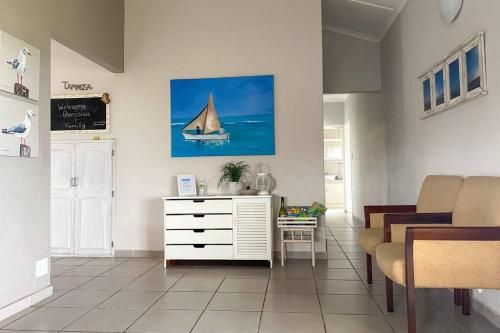 a living room with a white dresser and a sail boat on the wall at Tamassa Holiday Home on the Beach, in Port Edward in Port Edward