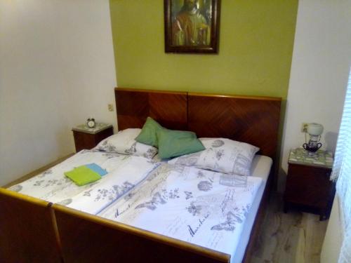 ein Bett mit weißer Bettwäsche und grünen Kissen darauf in der Unterkunft Chalupa 73 in Desov