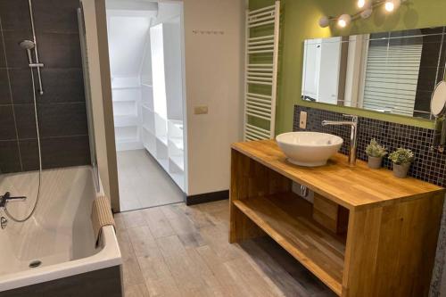 a bathroom with a sink and a mirror and a tub at À deux PATENIER de Dinant in Dinant