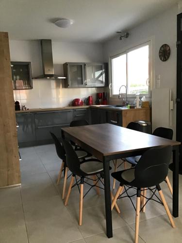 une cuisine avec une table en bois et des chaises noires dans l'établissement Charmante Maison idéalement située, à Saint-Gilles-Croix-de-Vie