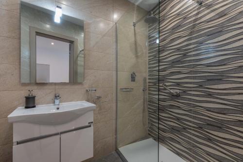 a bathroom with a sink and a shower with a mirror at White Sands in Mellieħa