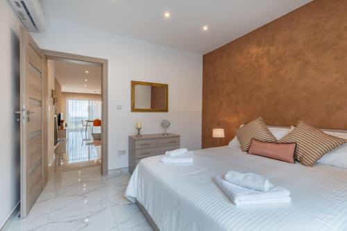 een slaapkamer met een groot wit bed en een spiegel bij White Sands in Mellieħa