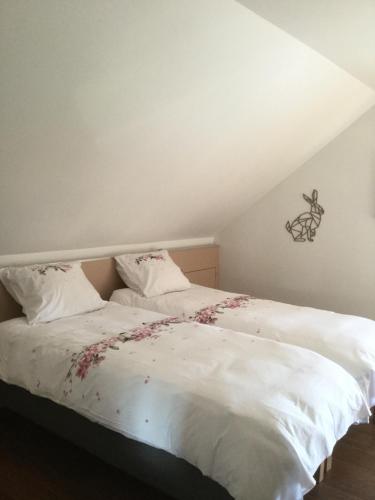 a bedroom with a white bed with flowers on it at Plumes et Pinceaux in Redu