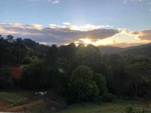 a sunset over a forest of trees with the sun setting at Valley Retreat in Currumbin Valley