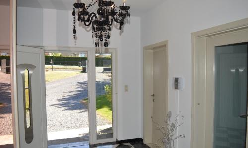 a chandelier hanging over a hallway with a doorway at Maison de vacances privative à louer in Aywaille