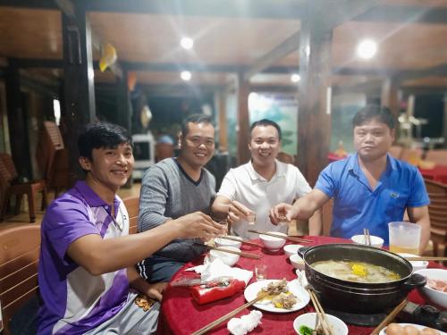 a group of men sitting around a table eating food at Ba Be Green Homestay in Bak Kan