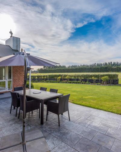 a patio with a table and chairs and an umbrella at Gem bed and breakfast in Christchurch