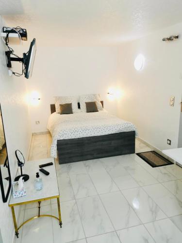 a white bedroom with a bed and a table at Agréable studio à proximité de Paris et Henri Mondor in Créteil