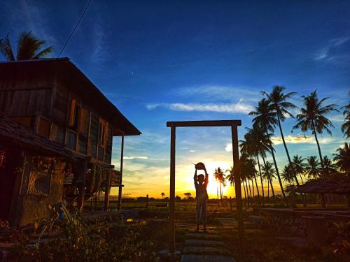 a person standing in a frame with their arms in the sunset at Sunset Homestay by Harry & Mimin in Telaga