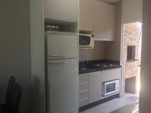 a kitchen with a refrigerator and a microwave at Casa Enseada próximo ao mar e comércios com 2 ar split in São Francisco do Sul