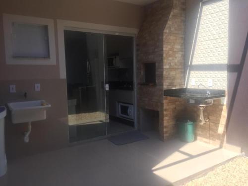a bathroom with a sink and a glass shower at Casa Enseada próximo ao mar e comércios com 2 ar split in São Francisco do Sul