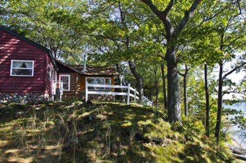 ein rotes Haus auf einem Hügel mit Bäumen in der Unterkunft Main Cabin - STARRY NIGHTS cabin in Carp Lake