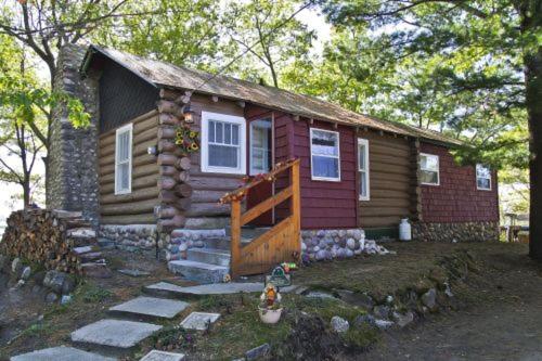 uma pequena cabana de madeira com um alpendre e uma casa em Main Cabin - STARRY NIGHTS cabin em Carp Lake