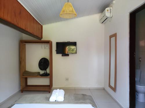 a room with a bathroom with a tv on the wall at Pousada Sitio das Flores in Trindade