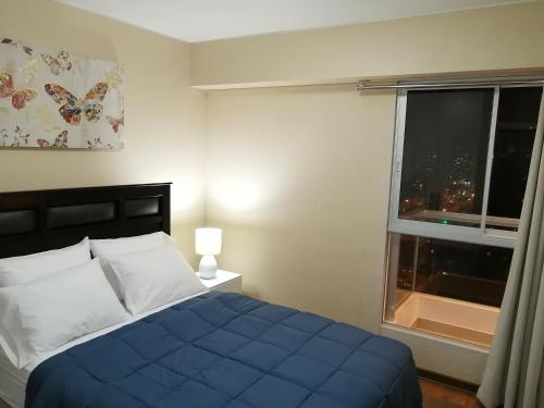Un dormitorio con una cama azul y una ventana. en Departamento BH South, en Lima