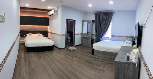 a hotel room with two beds and a desk at TAMU KoGURU in Jertih