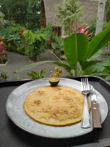 a pancake on a plate with a fork and knife at Coconut Tree Cottages in Batukaras