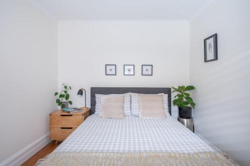 a white bedroom with a bed and a wooden nightstand at Mark and Kate's Place in Bendigo