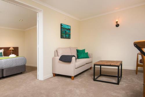 a living room with a chair and a bed at Furneaux Lodge in Endeavour Inlet
