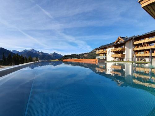 a swimming pool with a view of the mountains at Hotel Bergblick 5 Sterne in Grän