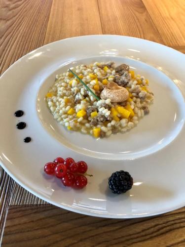 a plate of food with rice and fruit on a table at Hotel Isolabella Wellness in Fiera di Primiero