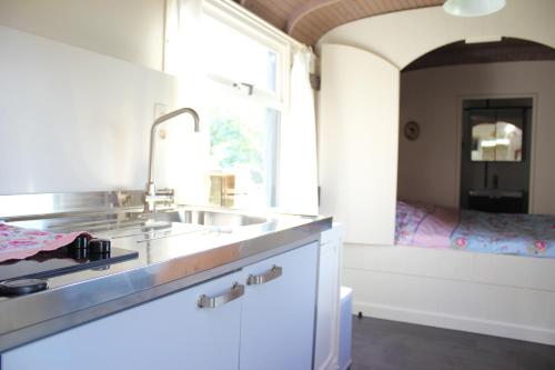 uma cozinha com um lavatório e um quarto com uma cama em Pipowagen De Molenkreek em Sint-Margriete