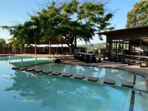 a swimming pool with benches and trees and a building at El Roi Guest Lodge in White River