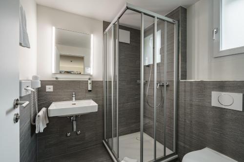 a bathroom with a glass shower and a sink at Hotel Bernerhof in Interlaken