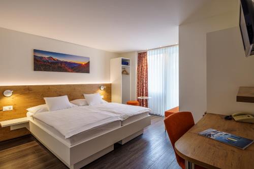 a bedroom with a bed and a desk and a table at Hotel Bernerhof in Interlaken