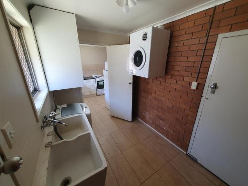 uma casa de banho com um lavatório e uma parede de tijolos em Stroll to the City Center in Minutes em Toowoomba