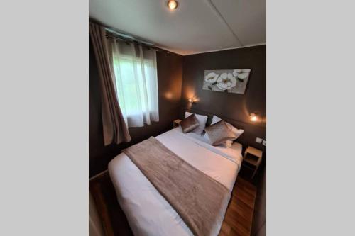 une chambre avec un lit avec des draps blancs et des oreillers dans l'établissement Le cottage, à Jeanménil