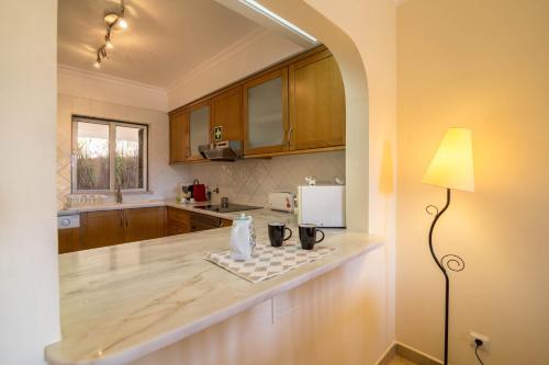 een keuken met houten kasten en een tafel met een lamp bij Clube Albufeira Apartment in Albufeira