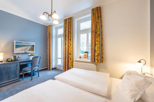 a bedroom with a bed and a desk and a window at Hotel Garni Getreuer Eckart in Binz