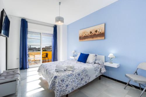 een slaapkamer met een bed met blauwe muren en een raam bij Milestone House in Rincón de la Victoria