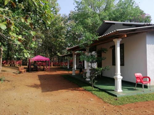 a house with red chairs and a pink tent at The Cascade Lodge in Embilipitiya