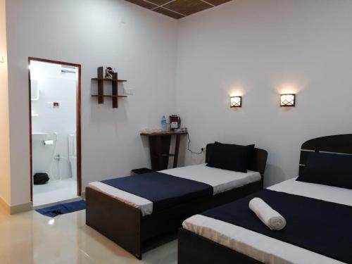 a room with two beds and a bathroom with a shower at The Cascade Lodge in Embilipitiya