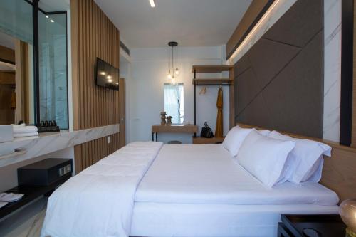 a bedroom with a large white bed and a mirror at ioniangems in Lefkada Town