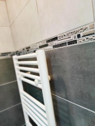 a metal shelf in a bathroom with tiles on the wall at Cosy Paris CDG Stade de France in Le Blanc-Mesnil