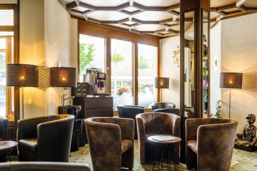 a bar with leather chairs and tables and windows at Hotel Bernerhof in Interlaken
