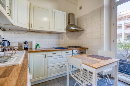une cuisine avec des armoires blanches et une table avec des chaises dans l'établissement IMMOGROOM - EXCLUSIVE - Terrace - Amazing quiet place - Wifi, à Cannes