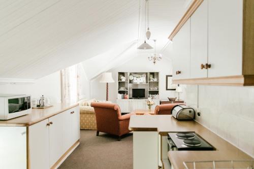 Knorhoek Country Guesthouse في ستيلينبوش: مطبخ وغرفة معيشة مع دواليب بيضاء