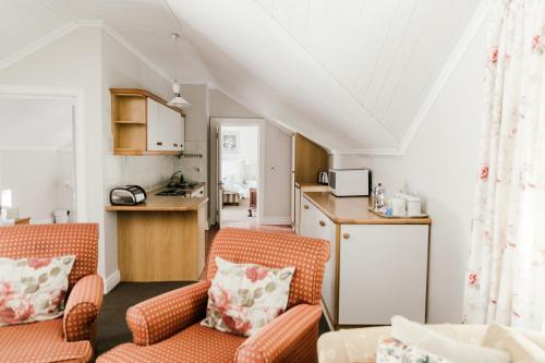 a living room with two chairs and a kitchen at Knorhoek Country Guesthouse in Stellenbosch