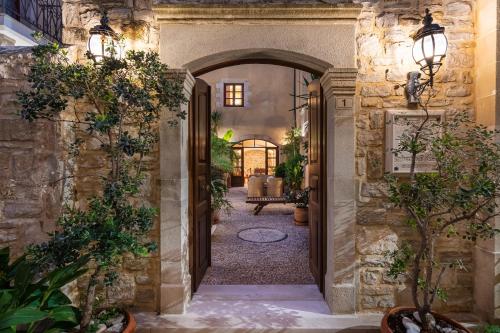 an entrance to a house with an archway with plants at Palazzino Di Corina in Rethymno