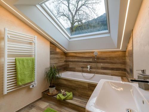 baño con tragaluz, bañera y lavamanos en Panorama Lodge, en Walchsee