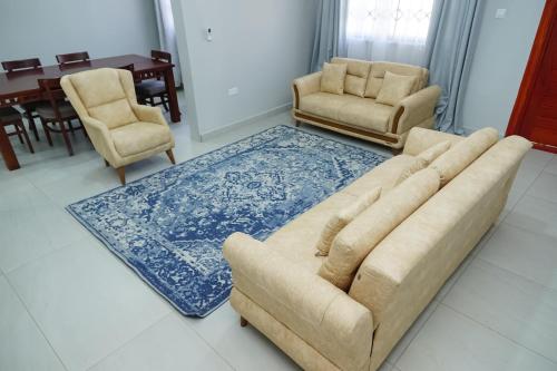 a living room with a couch and two chairs and a table at Greyville Apartments in Lusaka