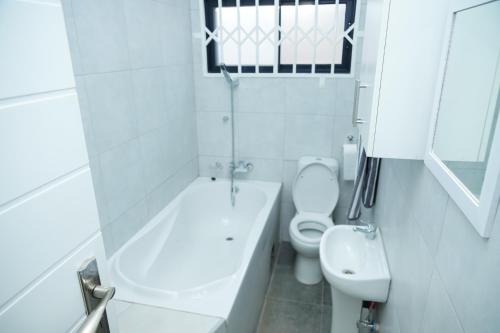 a white bathroom with a toilet and a sink at Greyville Apartments in Lusaka