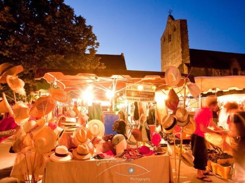 a group of people sitting at tables in a market at Cottage O' Temps de Vivre in Groléjac