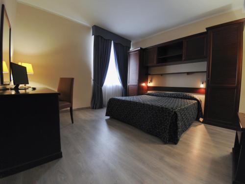a bedroom with a bed and a desk and a window at Hotel Mediterraneo in Civitavecchia