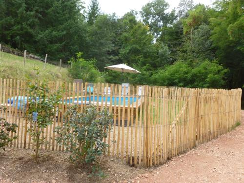 valla de madera con sombrilla junto a la piscina en la Bergerie du Bois Joannin 1497 route des fleuriats, en Iguerande